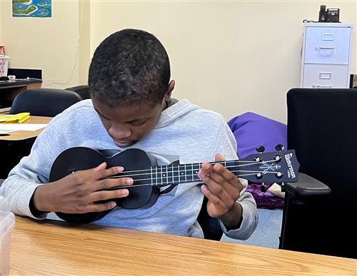 student playing with ukulele